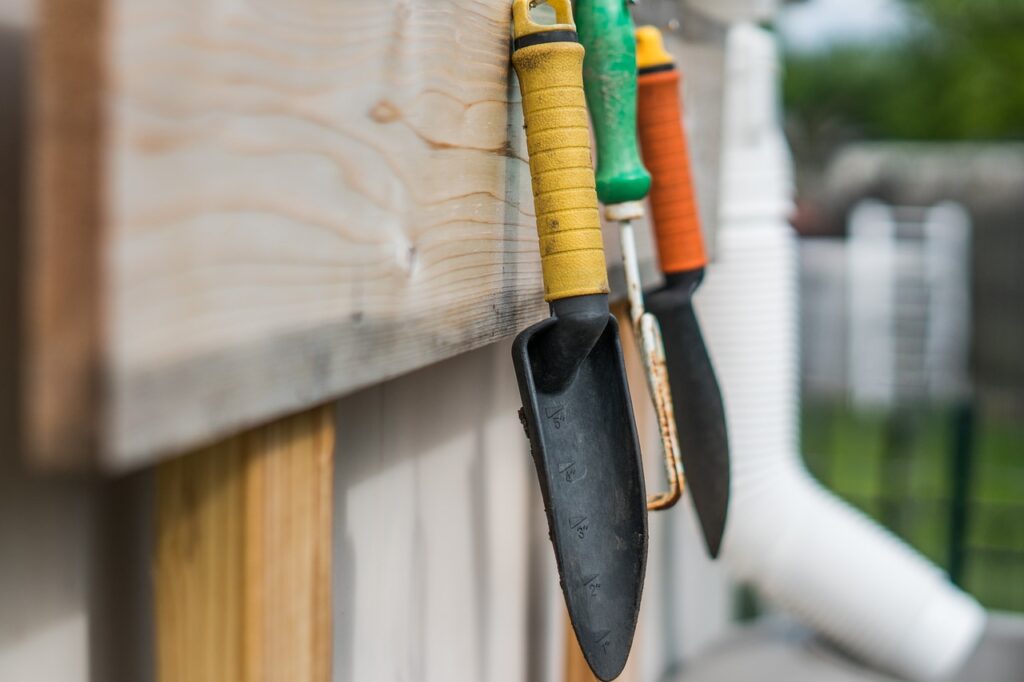 What garden tools do I need? A trowel and other tools hanging from wall