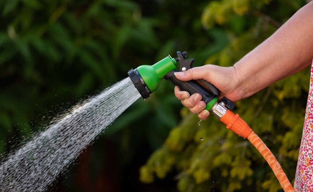 What garden tools do I need? A woman spraying a hose